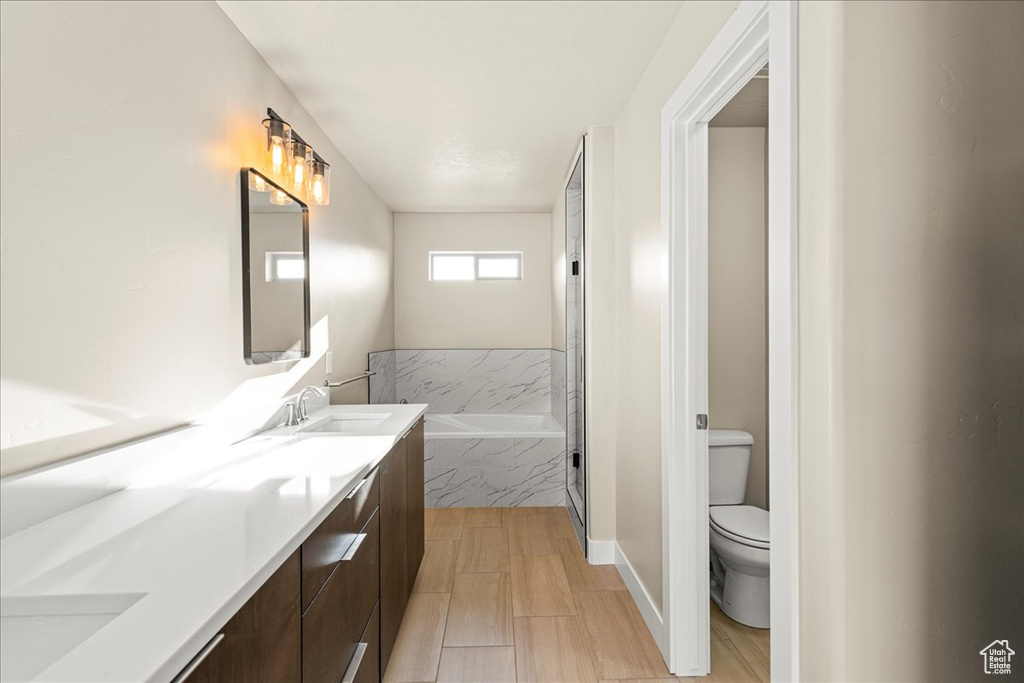 Full bathroom featuring toilet, a garden tub, and double vanity