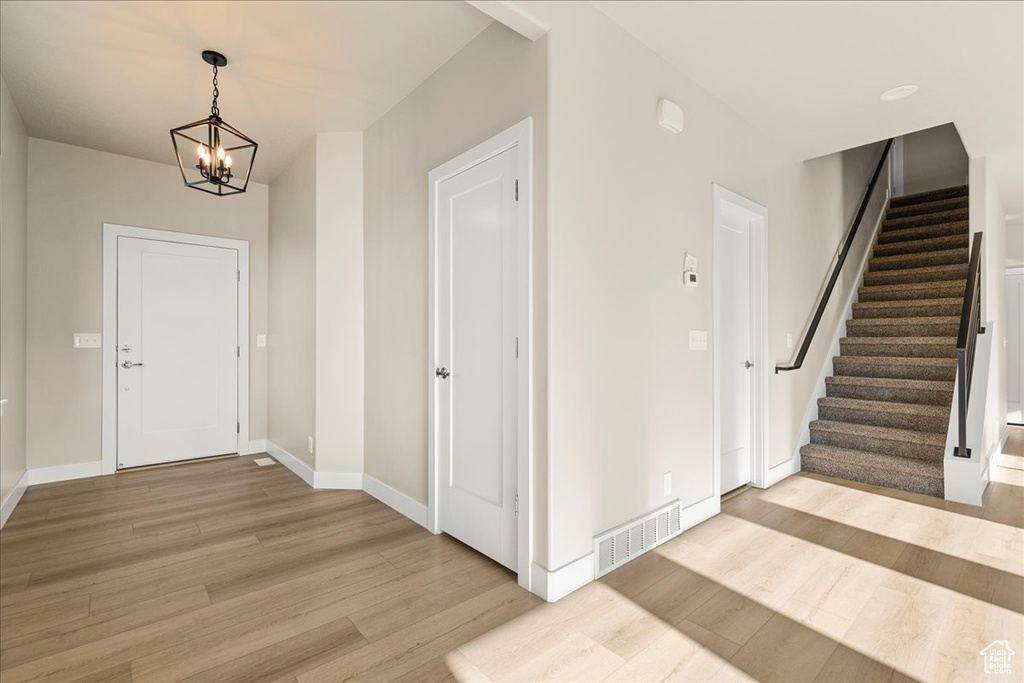 Foyer with light wood-style flooring, stairs, and a chandelier
