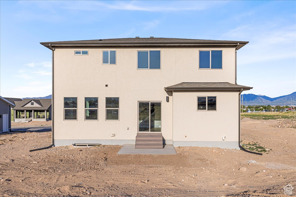 Back of house featuring a mountain view and stucco siding