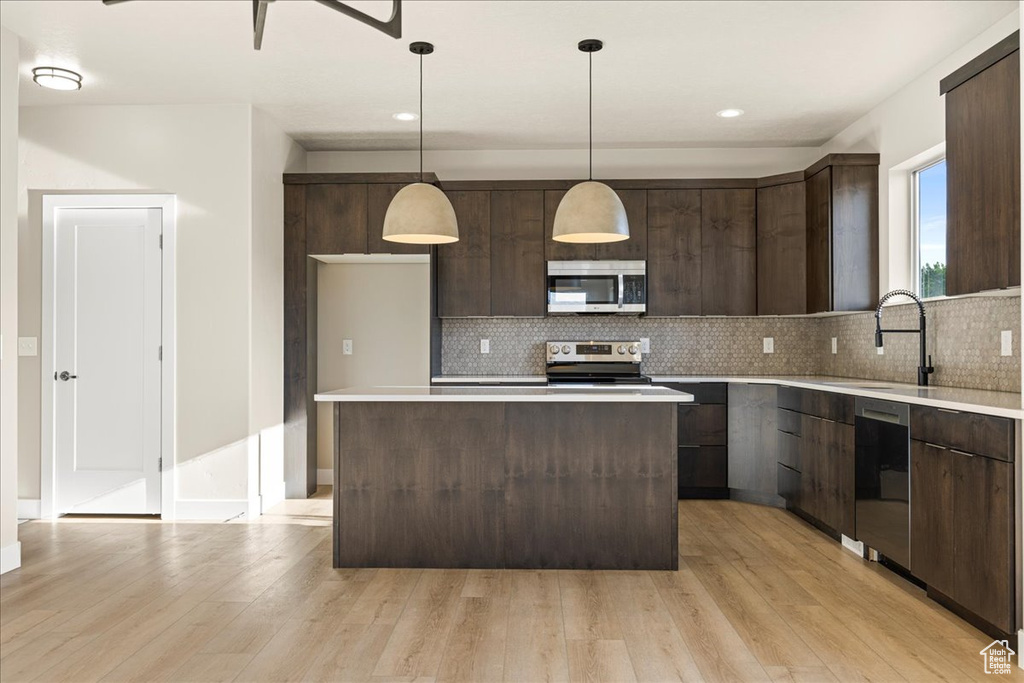 Kitchen featuring stainless steel appliances, a sink, modern cabinets, dark brown cabinets, and backsplash
