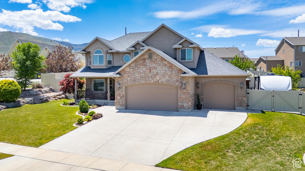 View of front facade featuring a gate, stone siding, stucco siding, and driveway