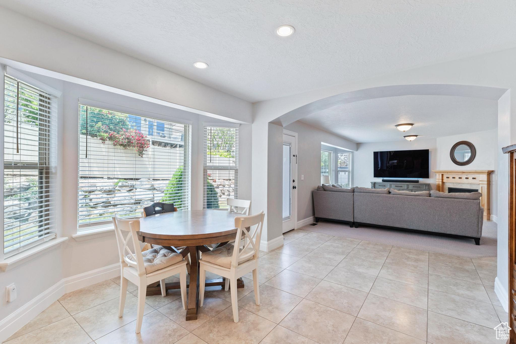 Dining room featuring arched walkways, baseboards, light tile patterned floors, recessed lighting, and a textured ceiling