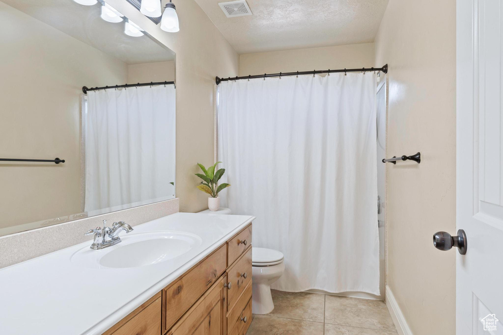 Bathroom with vanity, toilet, tile patterned flooring, curtained shower, and baseboards