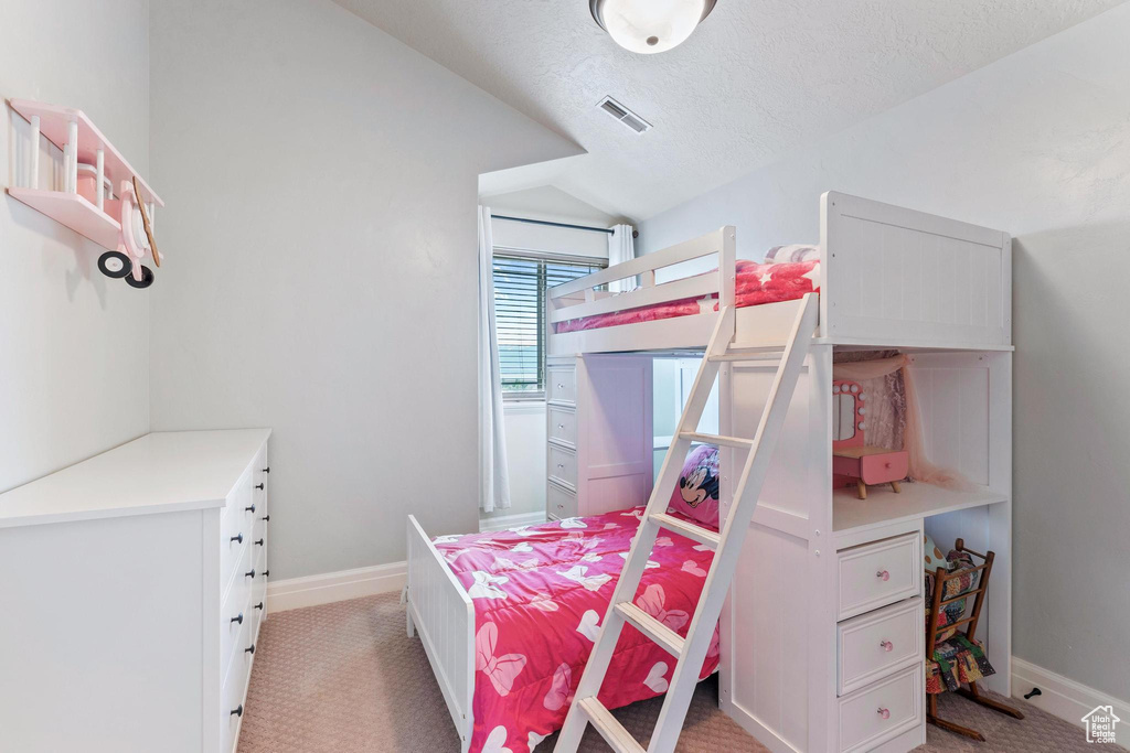 Bedroom featuring light carpet, vaulted ceiling, baseboards, and a textured ceiling