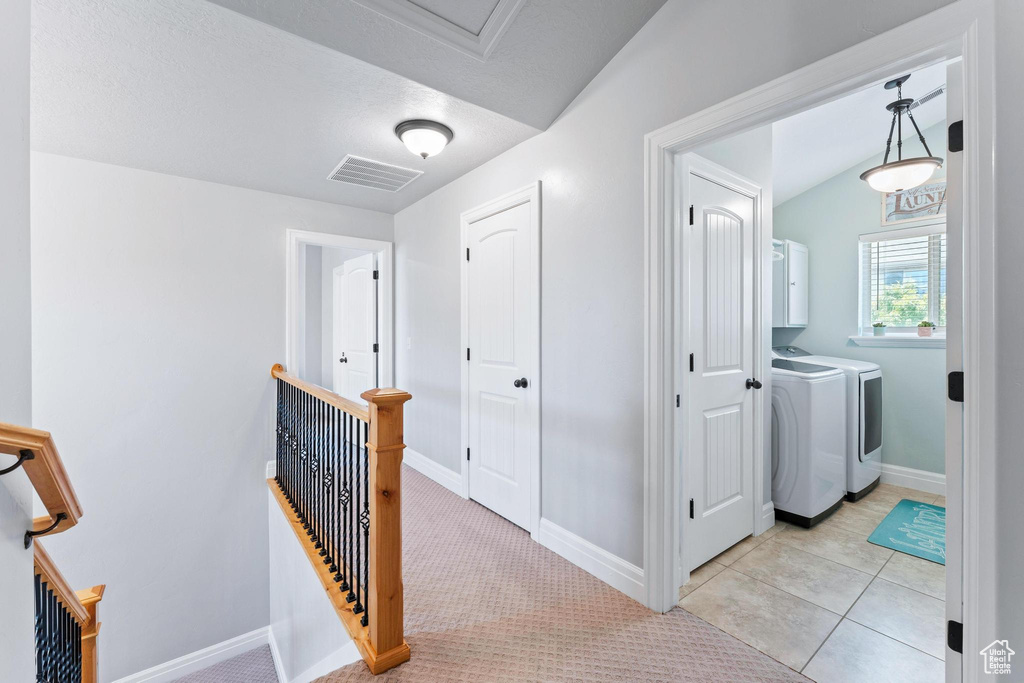 Hall featuring washer and clothes dryer, an upstairs landing, and baseboards