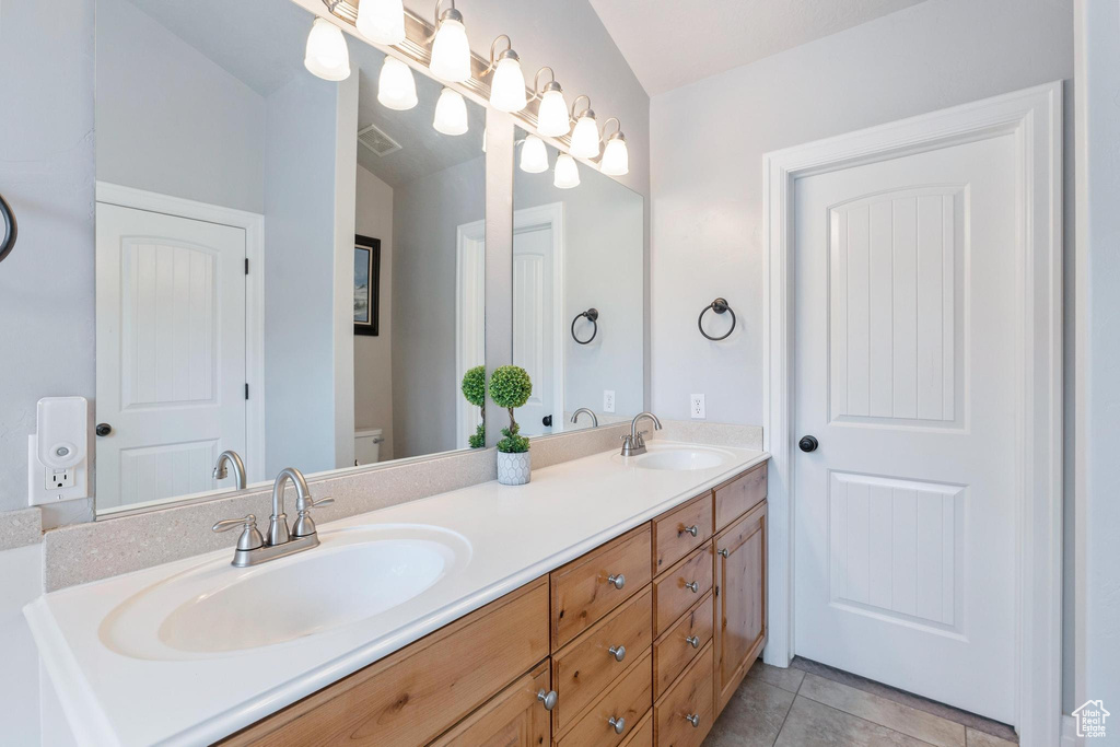 Full bath featuring double vanity, tile patterned floors, and toilet