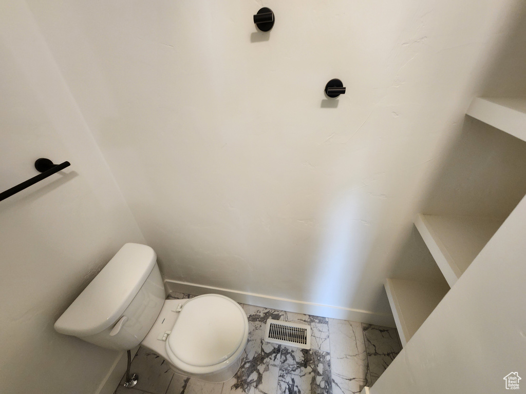 Bathroom with marble finish floors, toilet, and baseboards