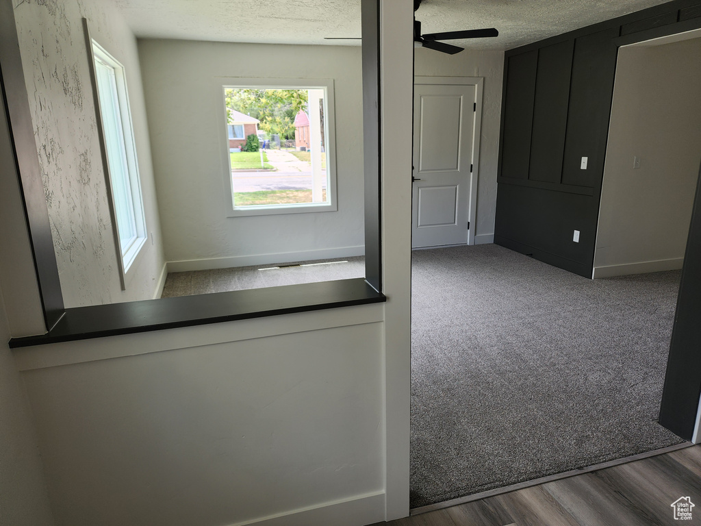Hallway featuring a textured ceiling, baseboards, and carpet floors