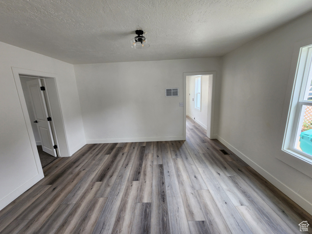 Spare room with wood finished floors, baseboards, and a textured ceiling
