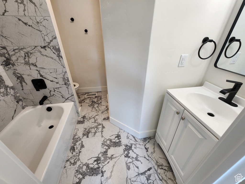 Bathroom with marble finish flooring, baseboards, vanity, and toilet