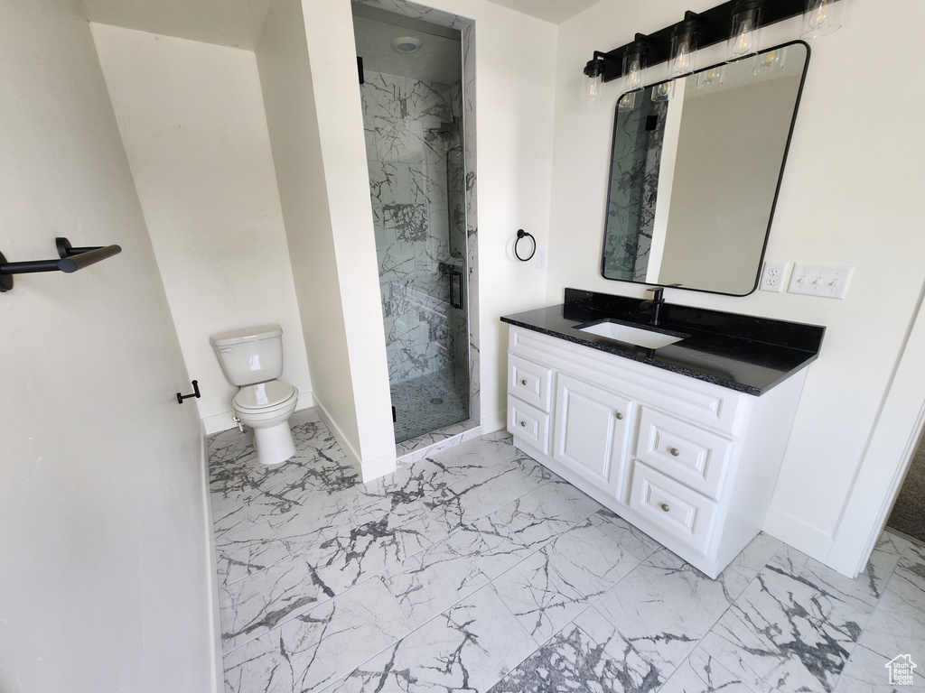 Full bath featuring marble look tile flooring, a marble finish shower, and baseboards