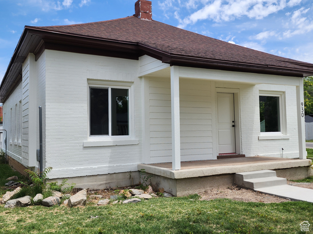 View of front of home featuring a chimney, a shingled roof, and brick siding