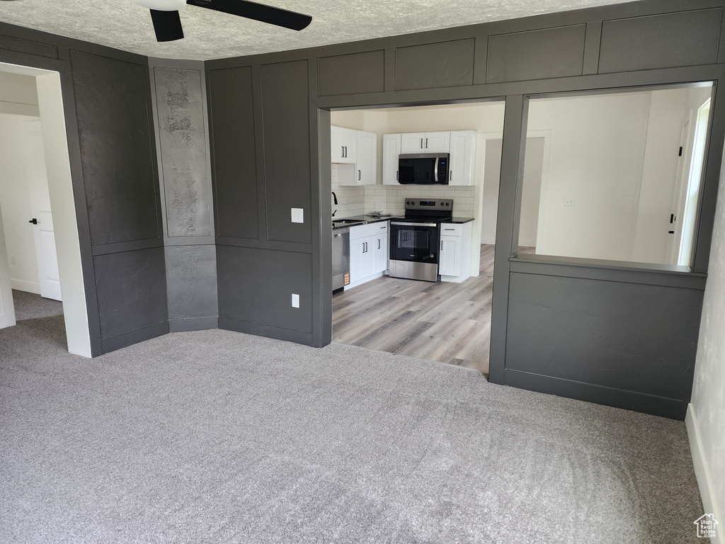 Spare room with ceiling fan, light colored carpet, and a sink