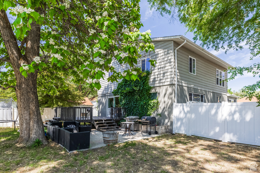 Rear view of house featuring a wooden deck and a patio area