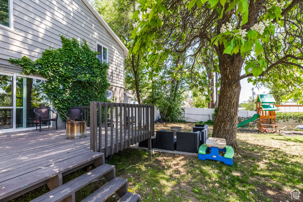 View of yard featuring a wooden deck and a playground
