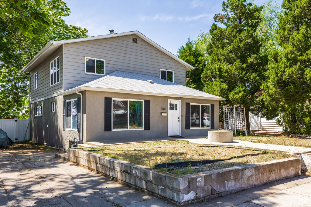 View of front of house featuring a shingled roof, a patio, and stucco siding