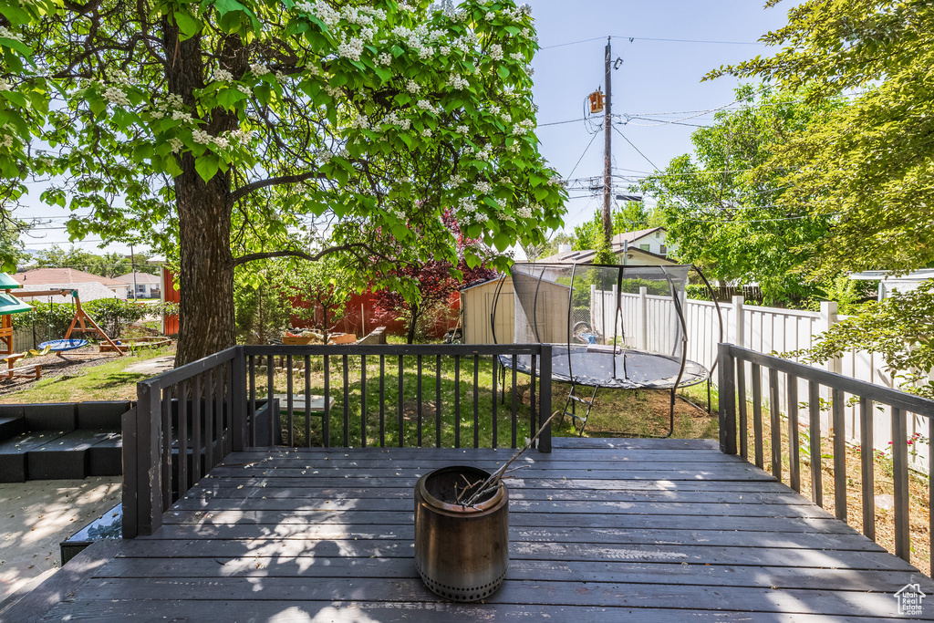 Wooden terrace featuring a trampoline and a fenced backyard