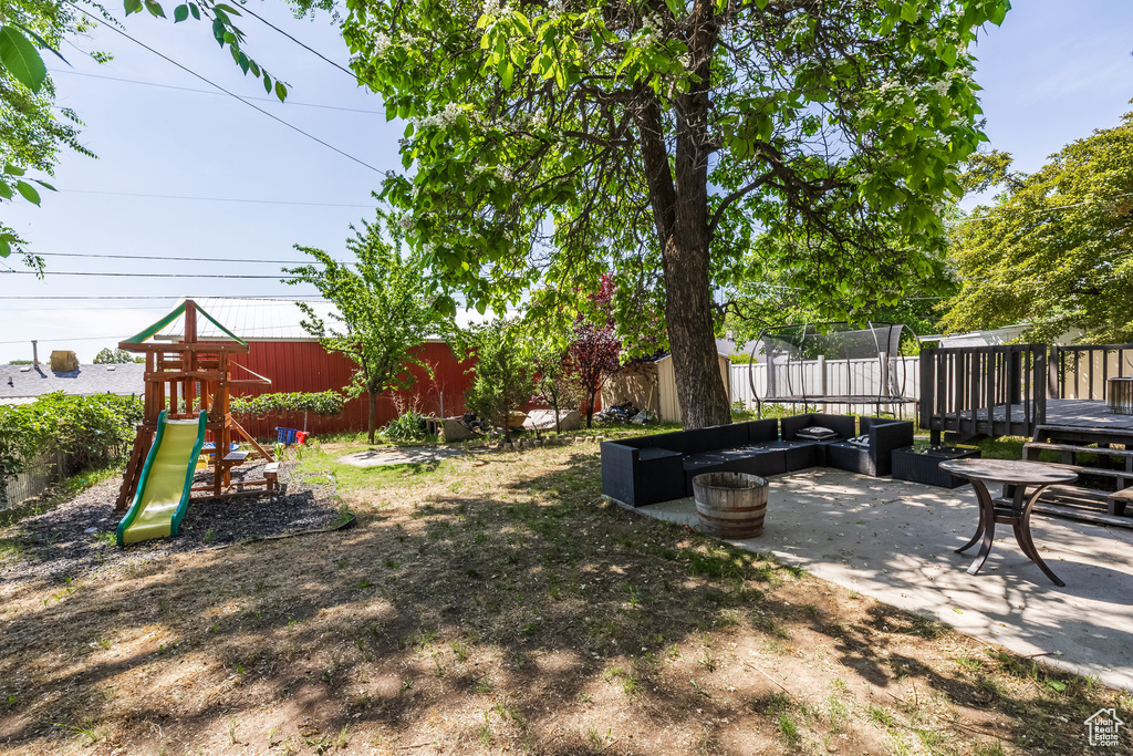 View of yard featuring a playground, a deck, and a patio