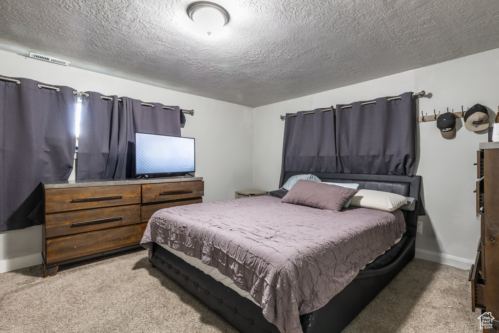 Bedroom featuring carpet, a textured ceiling, and baseboards