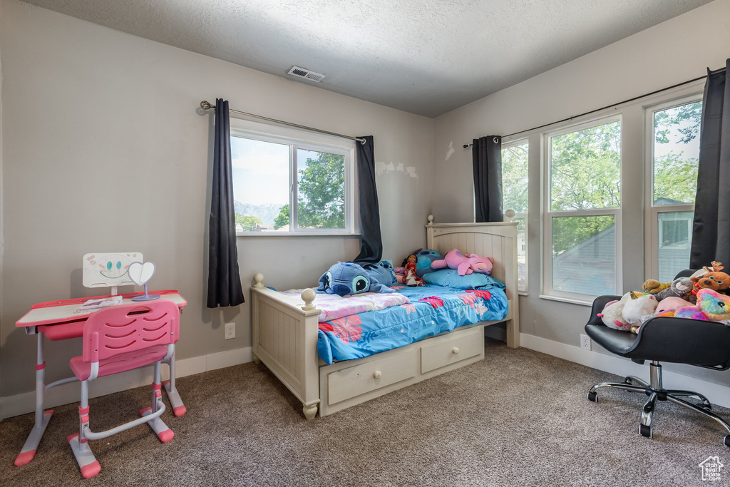 Carpeted bedroom featuring a textured ceiling and baseboards