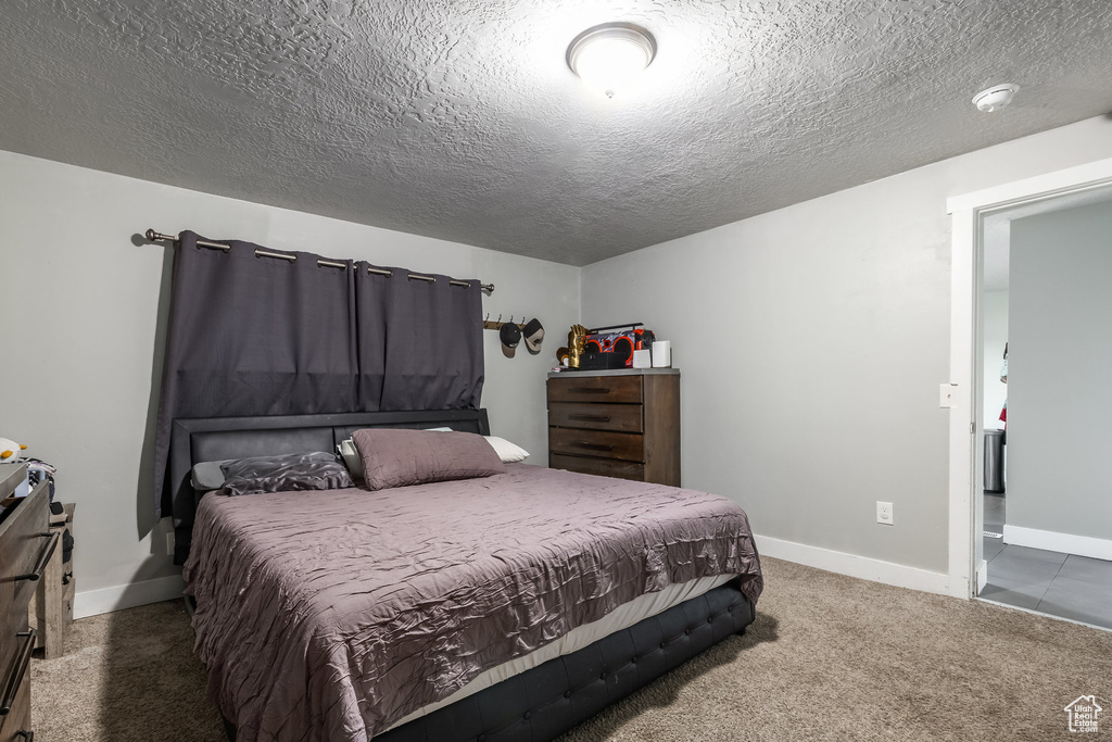 Carpeted bedroom with baseboards and a textured ceiling