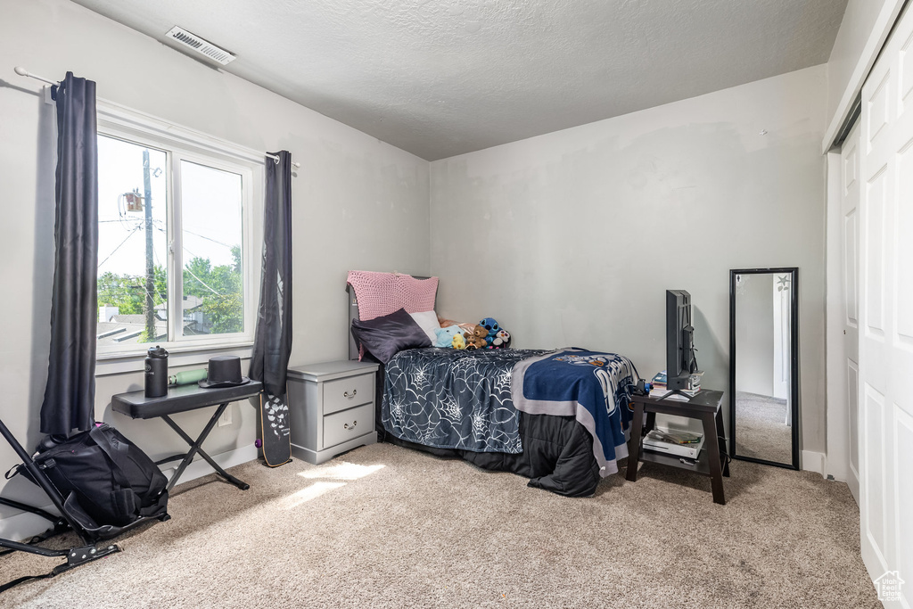 Carpeted bedroom with a textured ceiling and baseboards