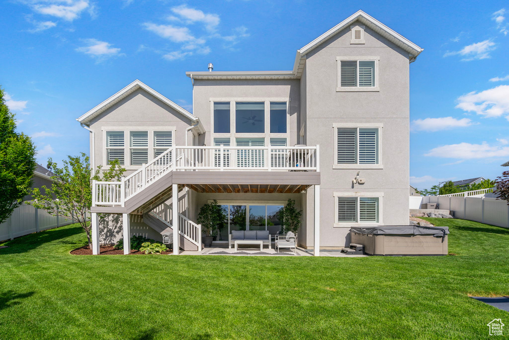 Rear view of property featuring a hot tub, an outdoor living space, stucco siding, a deck, and a patio