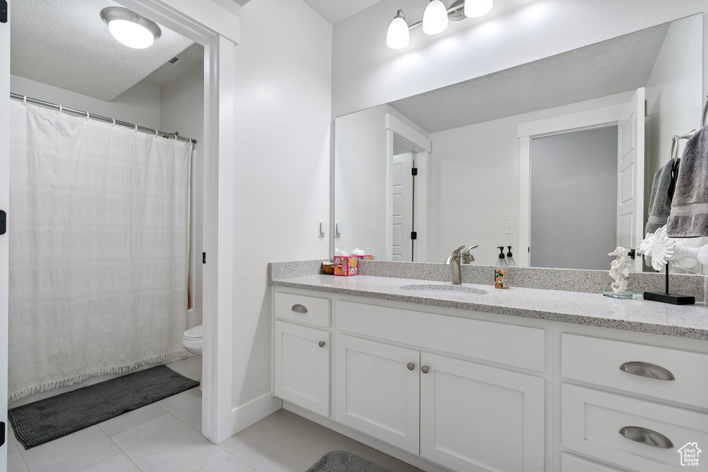 Bathroom featuring toilet, vanity, tile patterned floors, and a shower with curtain