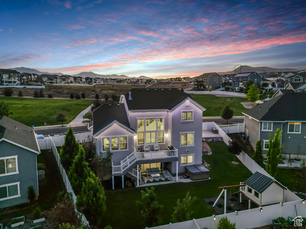 Back of house at dusk with a residential view, a deck, and stairway