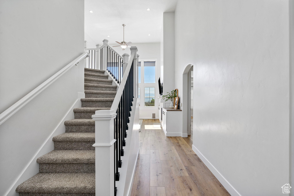 Stairway featuring arched walkways, wood-type flooring, a ceiling fan, recessed lighting, and baseboards