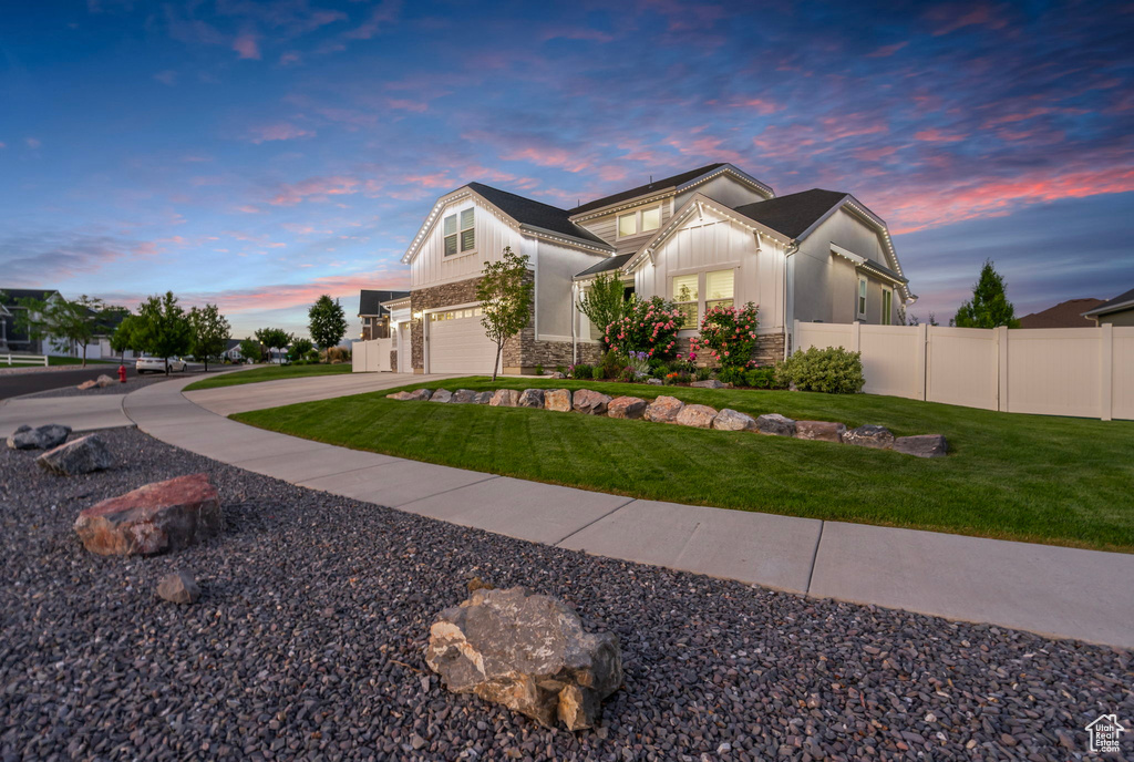 View of front facade featuring an attached garage, stone siding, board and batten siding, and concrete driveway