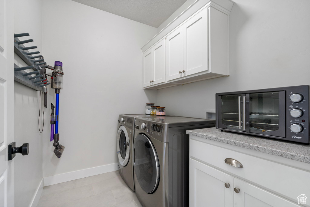 Laundry room featuring washing machine and dryer, cabinet space, and baseboards