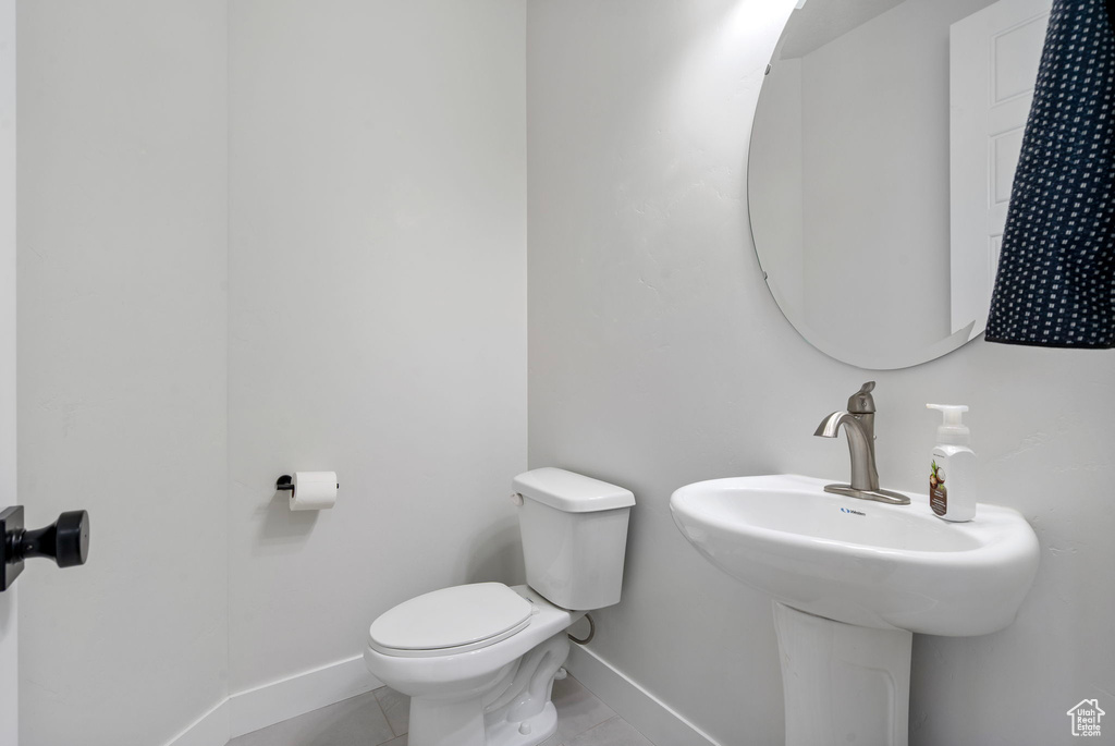 Bathroom with baseboards, toilet, and tile patterned flooring