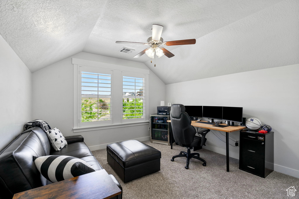 Office space featuring vaulted ceiling, a textured ceiling, ceiling fan, baseboards, and carpet floors