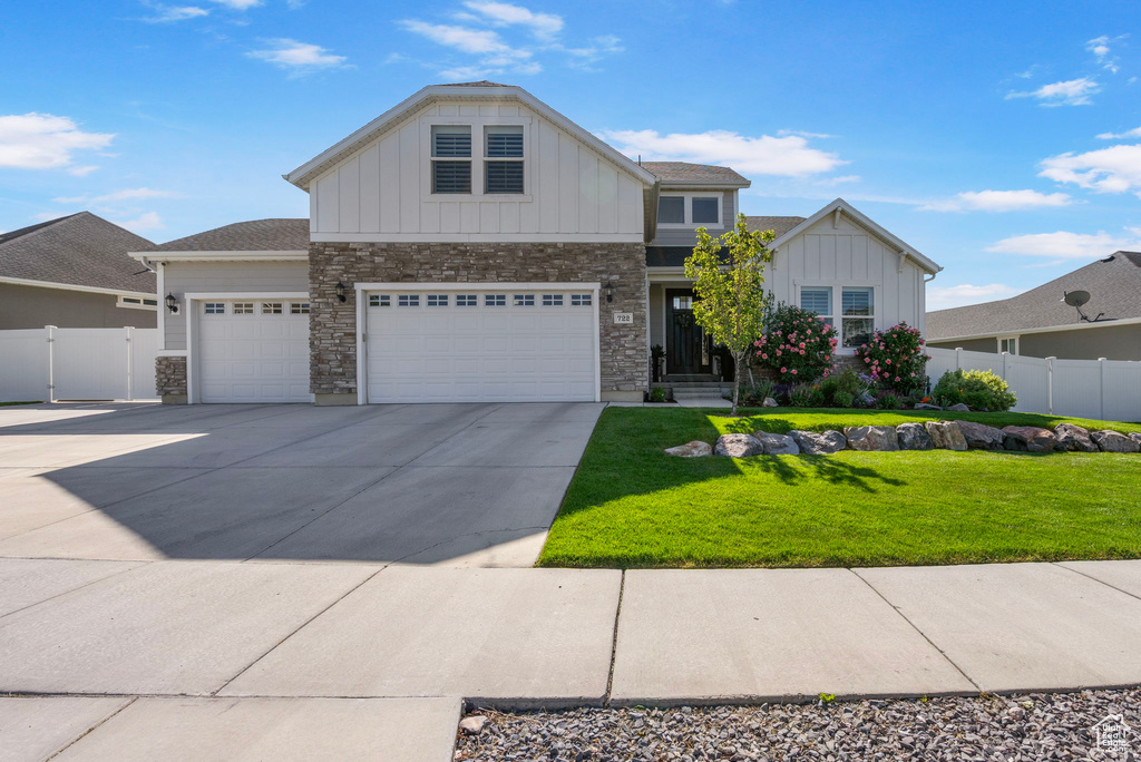 View of front of home with board and batten siding, stone siding, concrete driveway, a garage, and an attached garage
