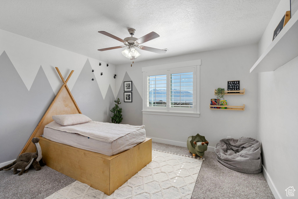 Bedroom featuring light carpet, baseboards, ceiling fan, and a textured ceiling