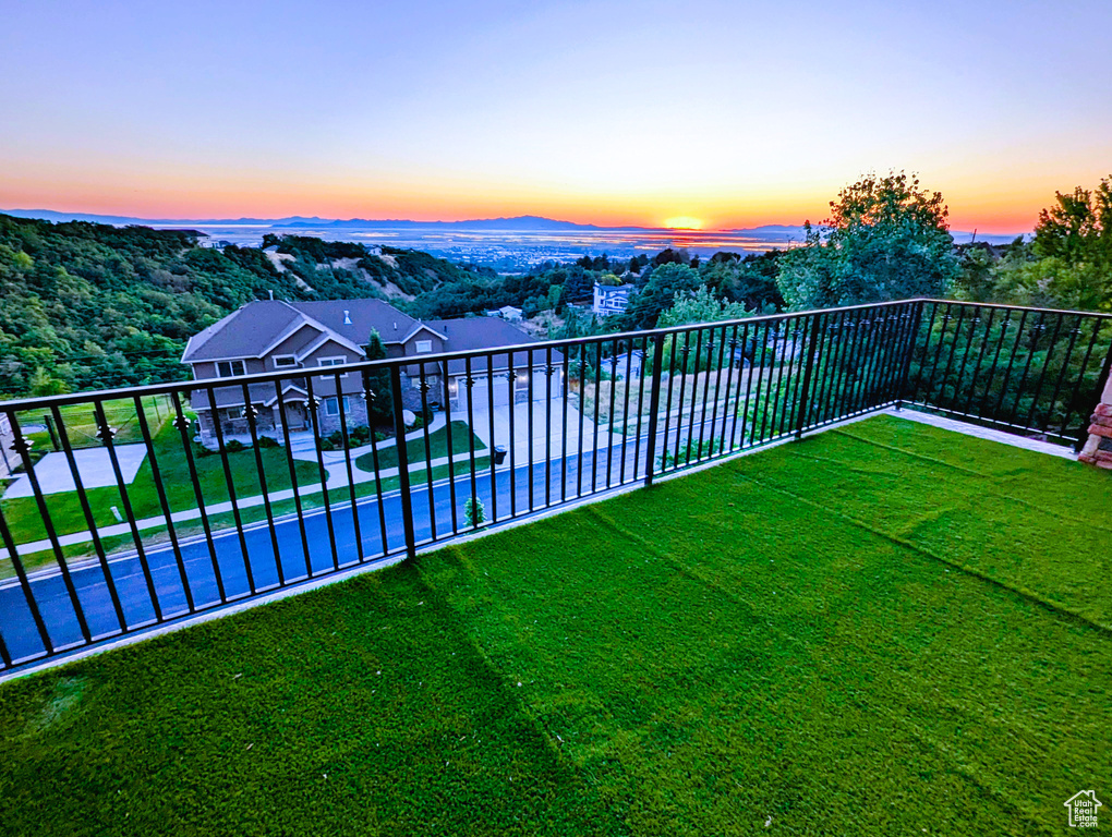 Yard at dusk featuring a balcony and a yard