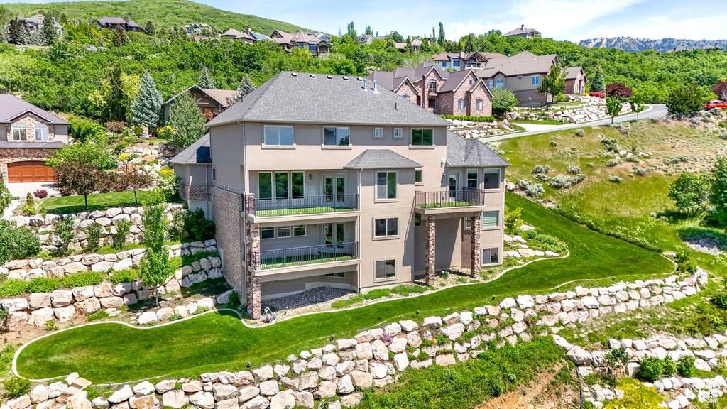 Back of property featuring a balcony, stucco siding, a residential view, and a mountain view