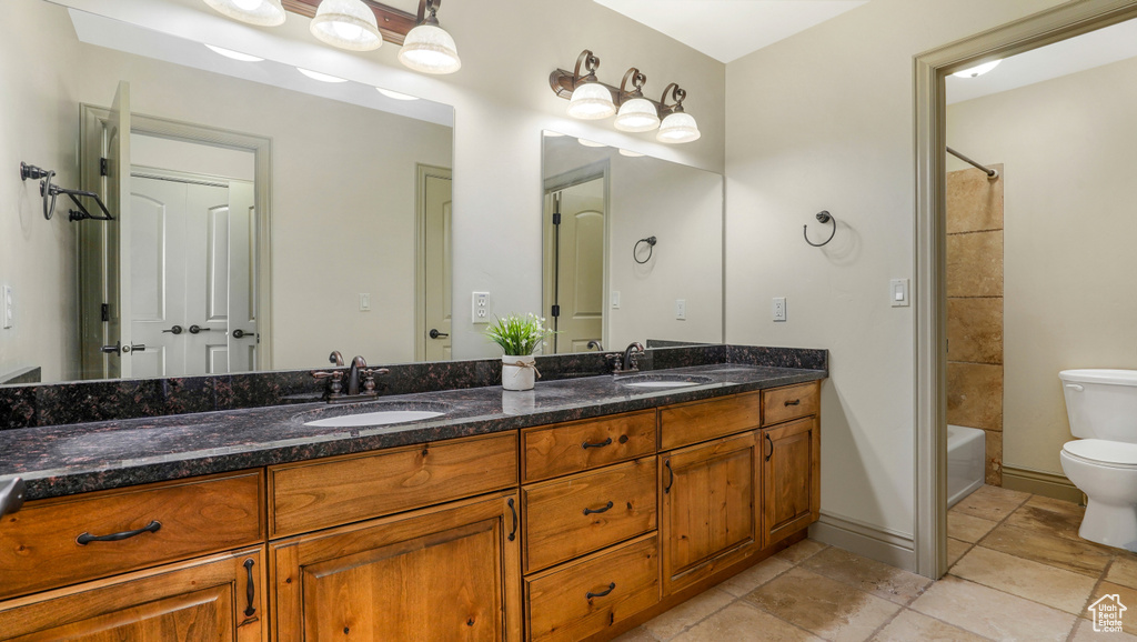 Bathroom featuring toilet, double vanity, and bathtub / shower combination