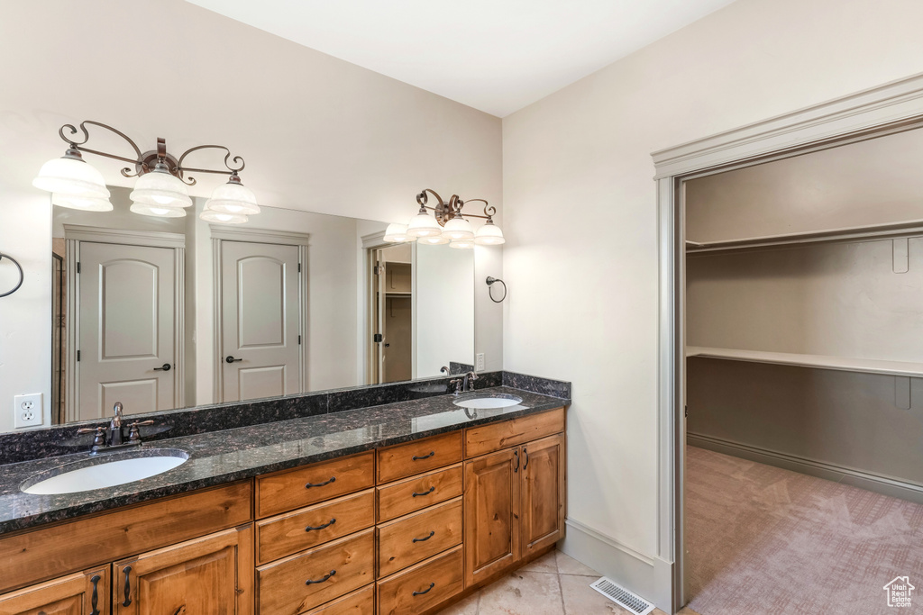 Full bath featuring double vanity, a walk in closet, and baseboards