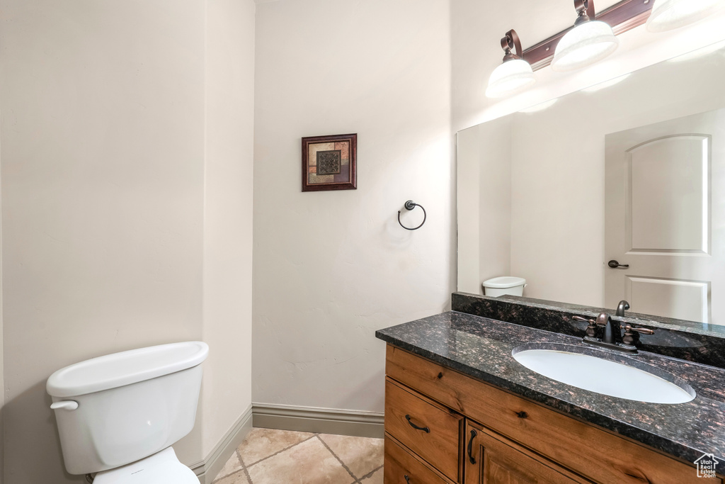 Bathroom with toilet, vanity, tile patterned flooring, and baseboards