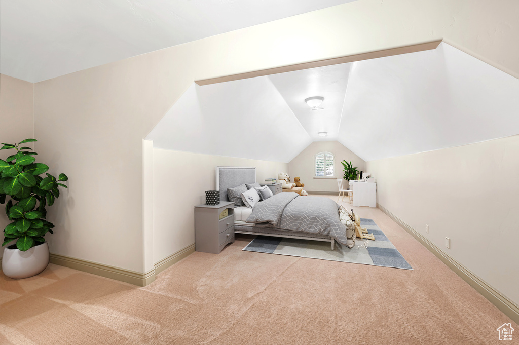Bedroom featuring light carpet, lofted ceiling, and baseboards