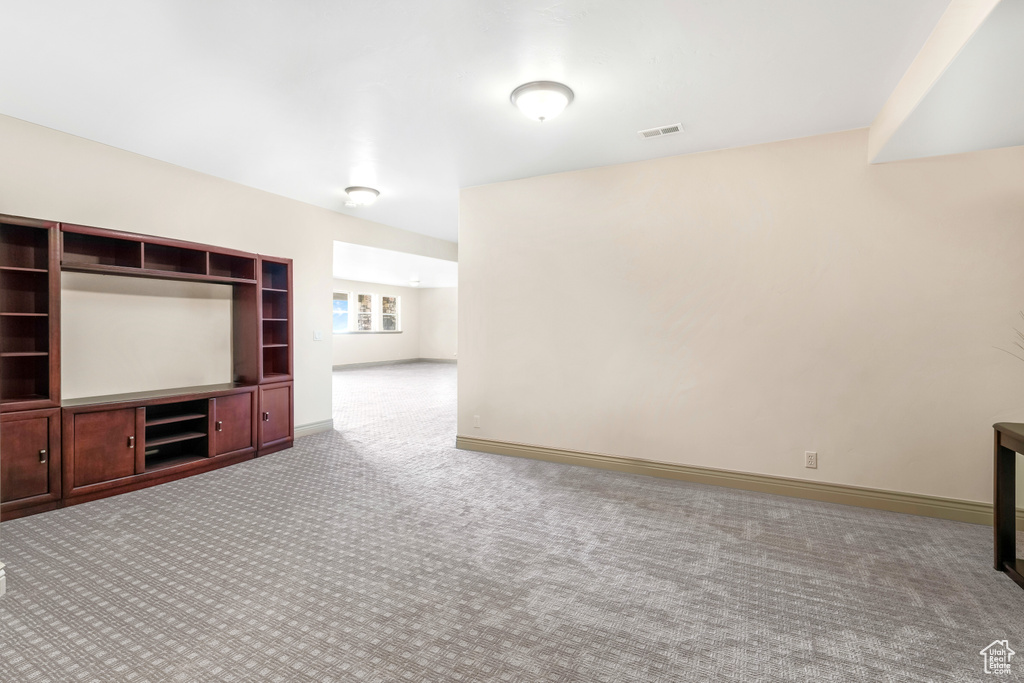 Unfurnished living room featuring carpet and baseboards
