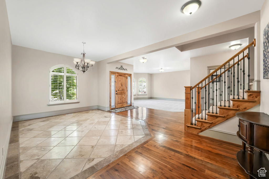 Foyer featuring baseboards, a chandelier, stairway, and wood finished floors