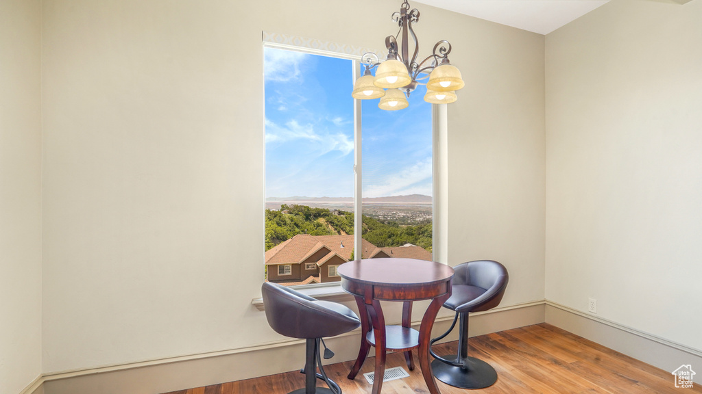 Dining room with wood finished floors, a chandelier, and baseboards