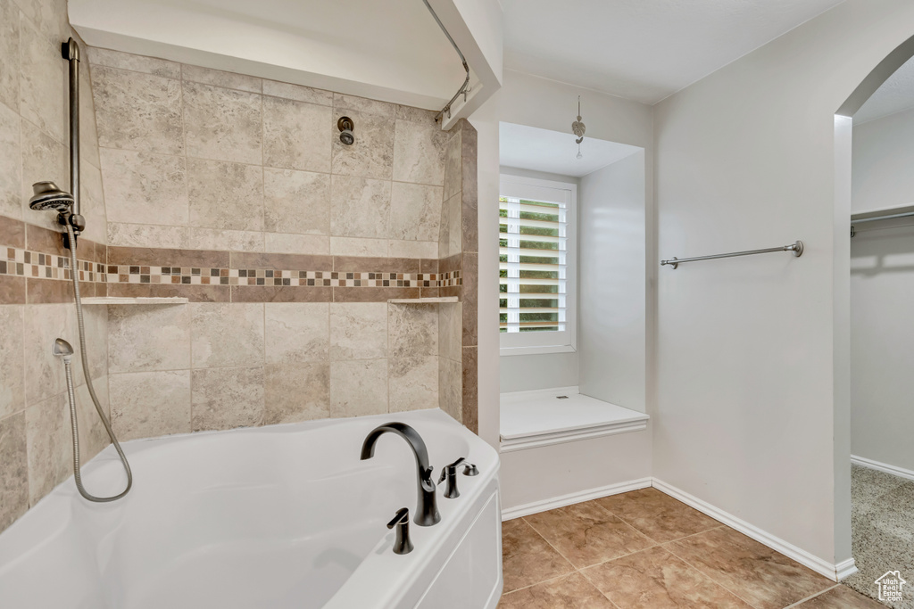Bathroom featuring a bath, a shower, a walk in closet, and baseboards