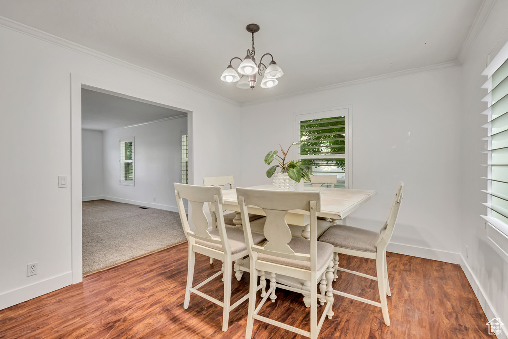 Dining room featuring a chandelier, ornamental molding, baseboards, and wood finished floors