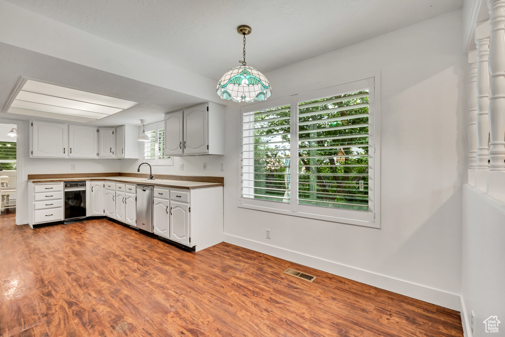 Kitchen with stainless steel dishwasher, baseboards, dark wood finished floors, and a sink