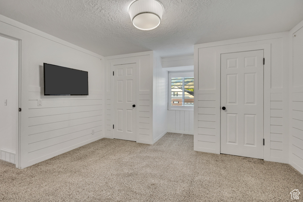 Unfurnished bedroom with a textured ceiling, carpet flooring, and a closet