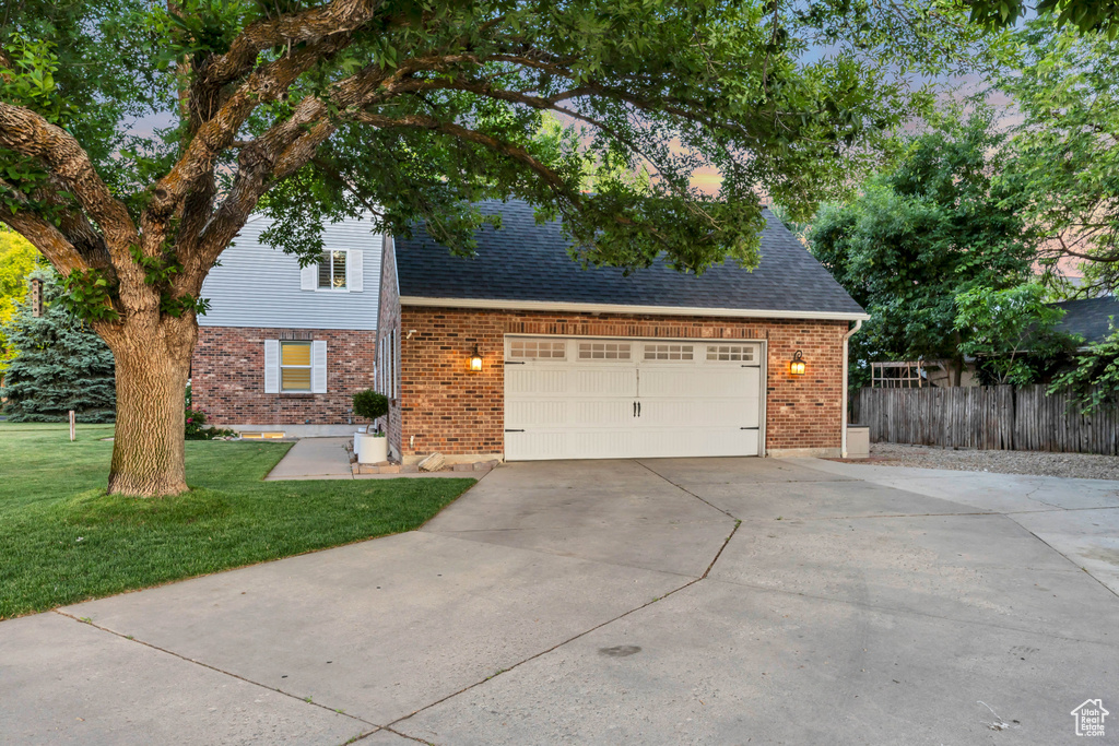 Traditional home with brick siding, concrete driveway, roof with shingles, and a garage